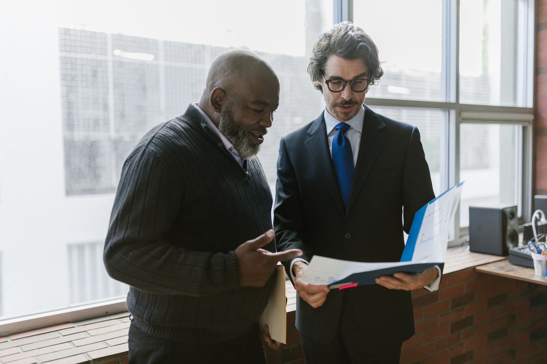 Main tenant un stylo au-dessus d'une liasse de documents imprimés sur un bureau clair