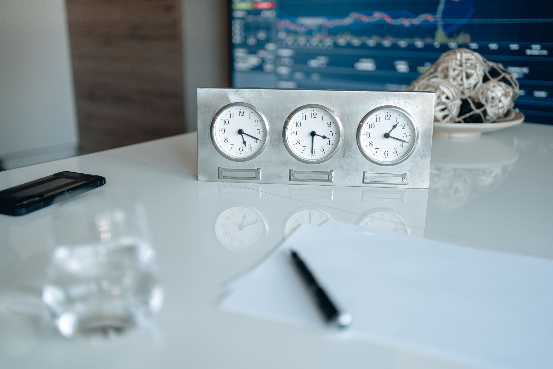 Horloge posée sur un bureau à côté d'un carnet ouvert et d'un stylo